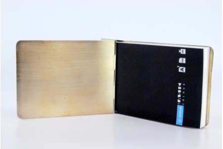 Porta bloco de notas em prata guilhochada com bandas ao longo e bloco no interior.